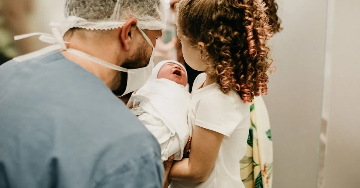A happy family moment as a young girl meets her newborn sibling in the hospital.